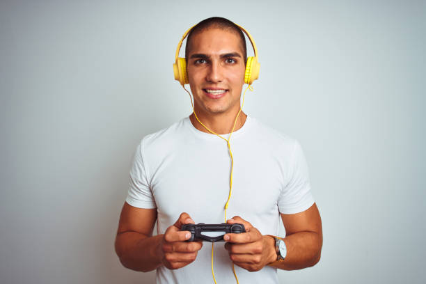 istock Young handsome man playing videogames using headphones over white isolated background with a happy face standing and smiling with a confident smile showing teeth 1162406121