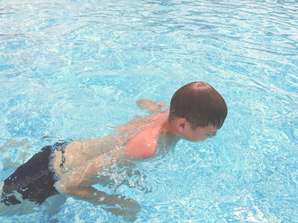 istock Teen guy swims in the pool 1162407009