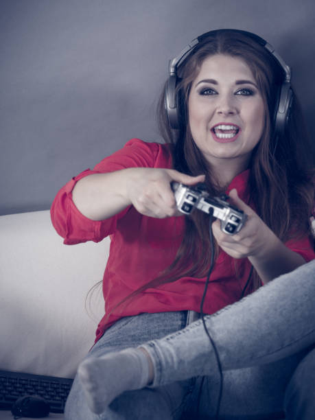 istock Young woman playing video games 1162408119