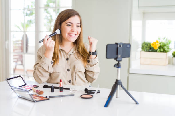 istock Beautiful young influencer woman recording make up video tutorial screaming proud and celebrating victory and success very excited, cheering emotion 1162408286