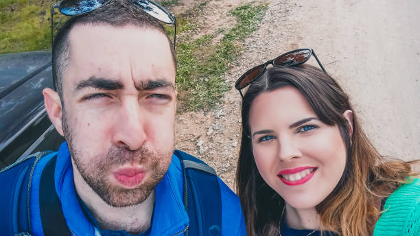 istock Happy young couple doing silly and funny faces while taking selfie picture with their smartphone or camera at the park 1162408753