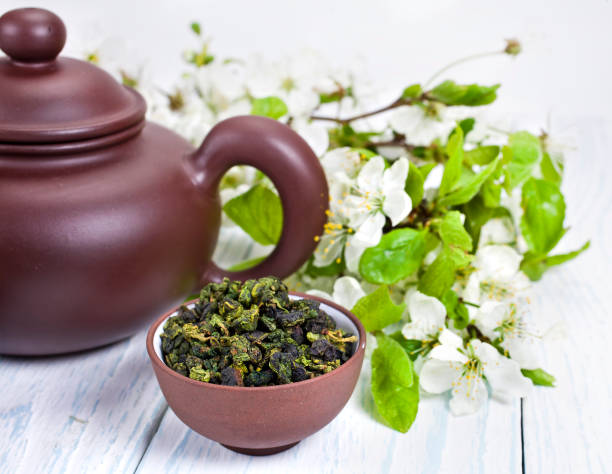 té verde seco y tetera de arcilla con ramas de manzano en flor - green tea cherry blossom china cup fotografías e imágenes de stock