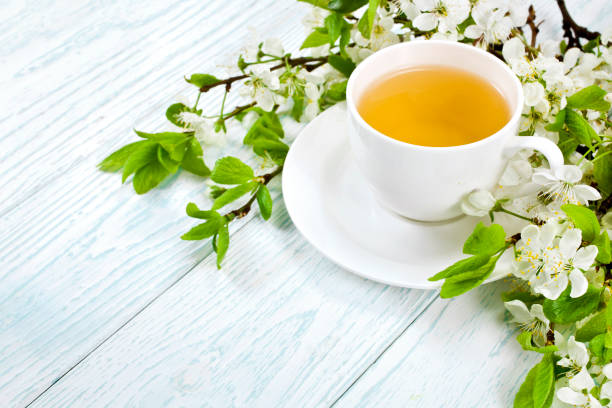 istock Green tea in a ceramic cup with branches of blossoming apple tree 1162408827