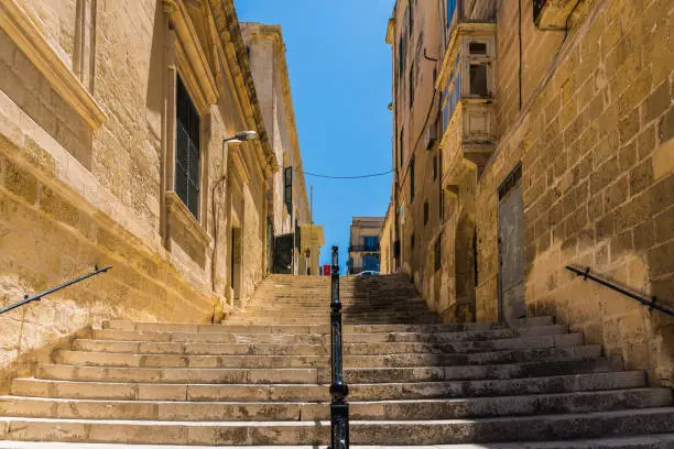 Photo of Old stone stairs between the ancient buildings with a blue sky on the background