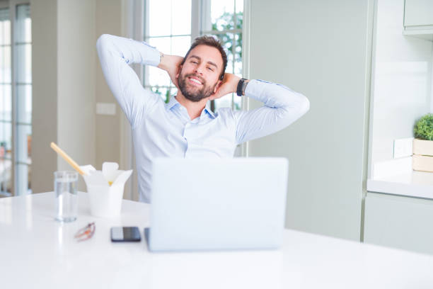istock Business man eating take away asian noodles food while working using computer laptop and smiling 1162410202
