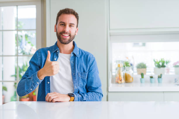 istock Handsome man at home doing happy thumbs up gesture with hand. Approving expression looking at the camera showing success. 1162410429