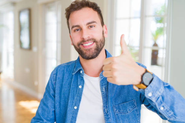 istock Handsome man at home doing happy thumbs up gesture with hand. Approving expression looking at the camera with showing success. 1162410505