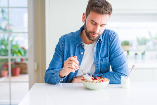 istock Handsome man having breakfast eating cereals at home and smiling 1162410586