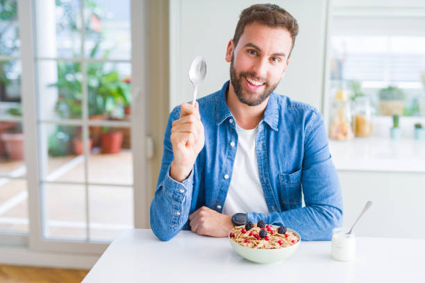 istock Handsome man having breakfast eating cereals at home and smiling 1162411144