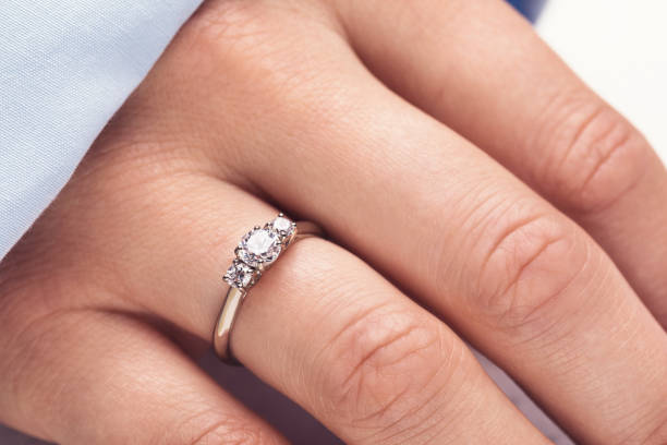 istock Golden ring with three diamonds on a female hand close up 1162411583