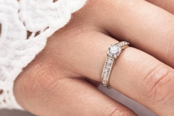 istock Gold engagement ring with diamonds on female hand, close-up 1162411624