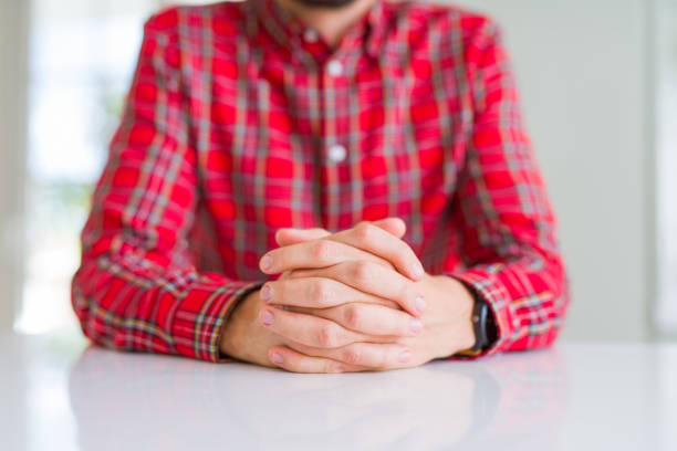 Close up of man crossed hands over white table