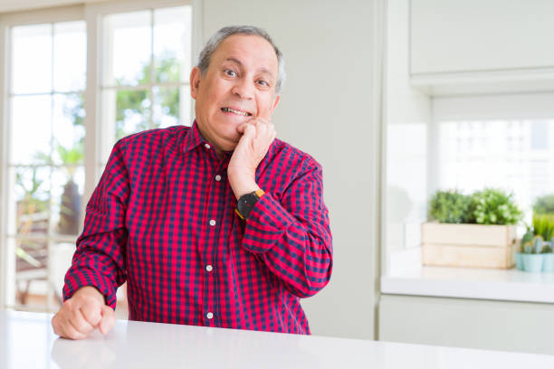 istock Handsome senior man at home looking stressed and nervous with hands on mouth biting nails. Anxiety problem. 1162412938