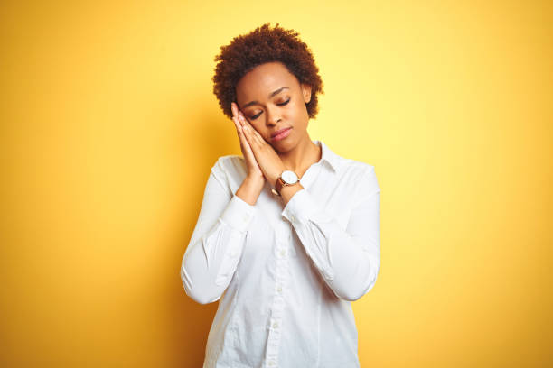 mulher de negócio do americano africano sobre o sono do fundo amarelo isolado que dorme cansado e que levanta com mãos junto ao sorrir com olhos fechados. - businesswoman black african descent studio shot - fotografias e filmes do acervo