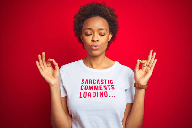 la donna afroamericana che indossa una maglietta con commenti sarcastici su sfondo rosso isolato si rilassa e sorride con gli occhi chiusi facendo un gesto di meditazione con le dita. concetto di yoga. - irony foto e immagini stock