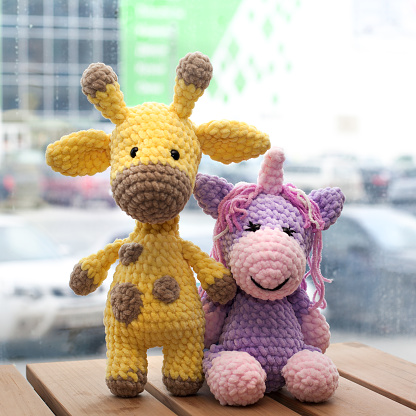 Crocheted amigurumi yellow giraffe and unicorn. Knitted handmade toy.