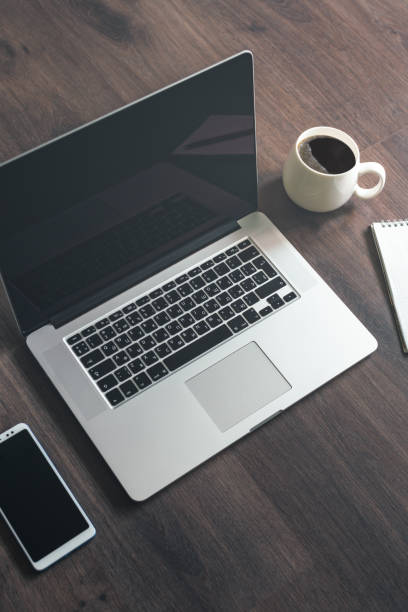Laptop, smartphone, notepad and cup of coffee on a wooden table