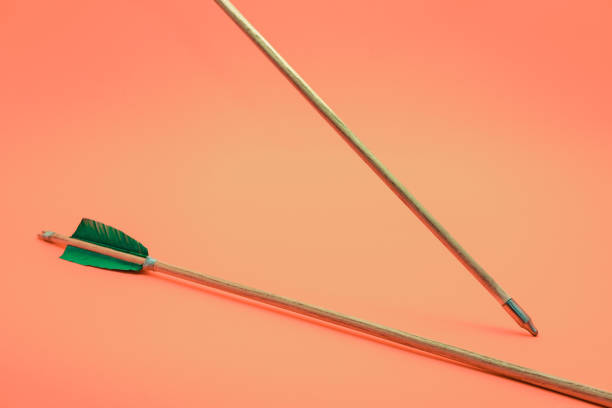 istock Old two green wooden arrow on a beautiful peach background. 1162422351