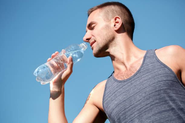 istock Healthy Lifestyle. Man practicing yoga outdoors standing with bottle drinkign water joyful close-up 1162423573