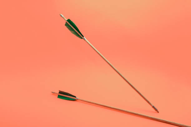 istock Old two green wooden arrow on a beautiful peach background. 1162424210