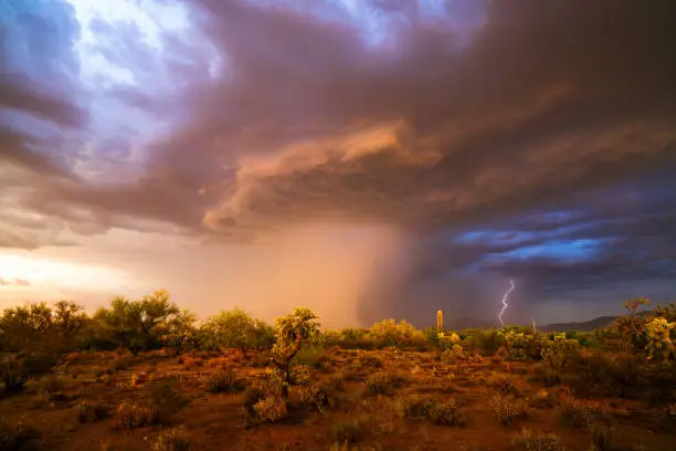 Dramatic, monsoon storm clouds with rain falling at sunset in the Arizona desert.