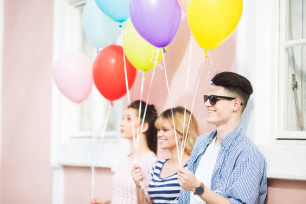 istock Beautiful young man holding balloons and smiling 1162427441