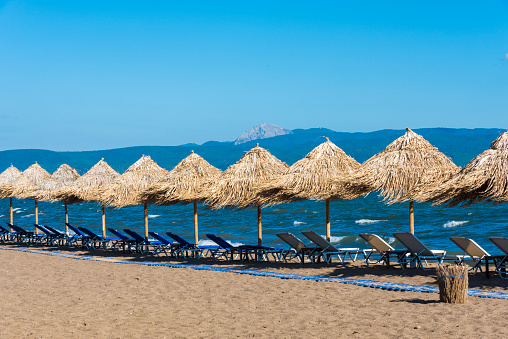 Sunbeds and wicker parasols on the sand beach at the Skala Kallonis, Mytilene, Greece