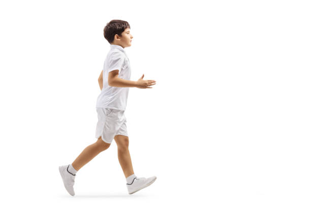 Full length profile shot of a boy in white shorts and t-shirt running isolated on white background