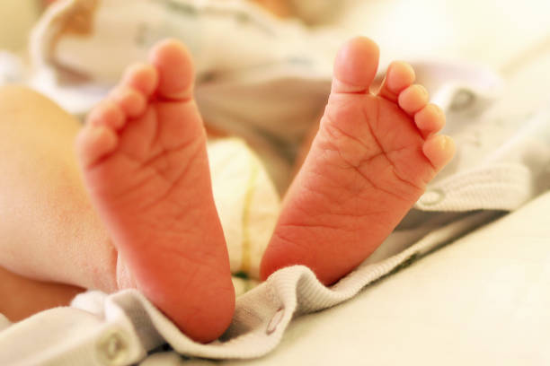 istock Tiny delicate feet of newborn baby on a bed. 1162431706