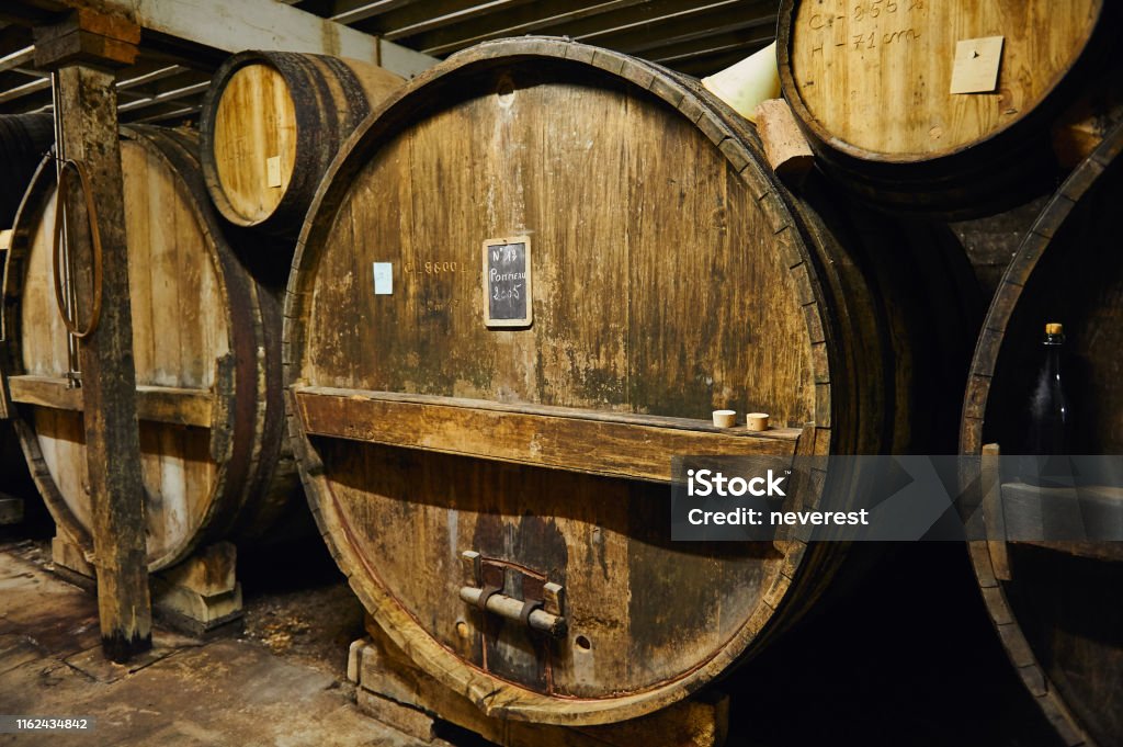 Big old oak casks of pommeau of calvados in a cellar Old oak casks with ageing traditional apple beverage of pommeau in a distillery cellar in Calvados region, Normandy, France Cider Stock Photo