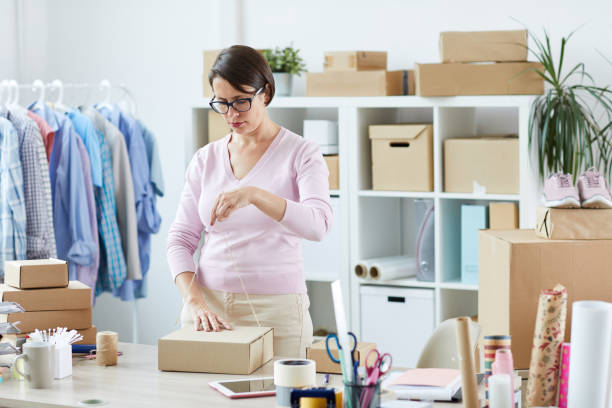 istock Manager of internet shop binding packed order of client with thread 1162440267