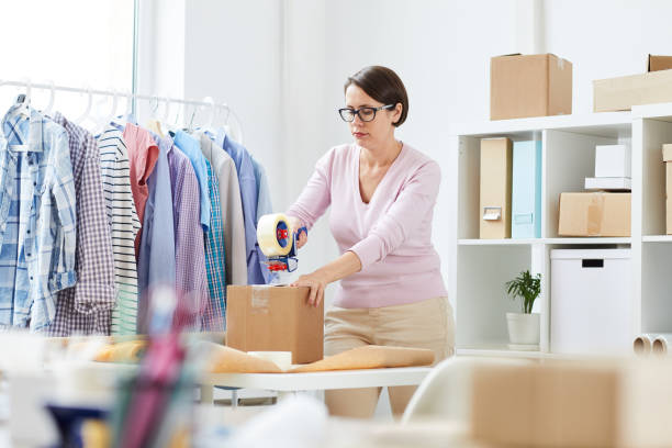 istock Young manager packing orders of clients and sealing boxes with adhesive tape 1162440334