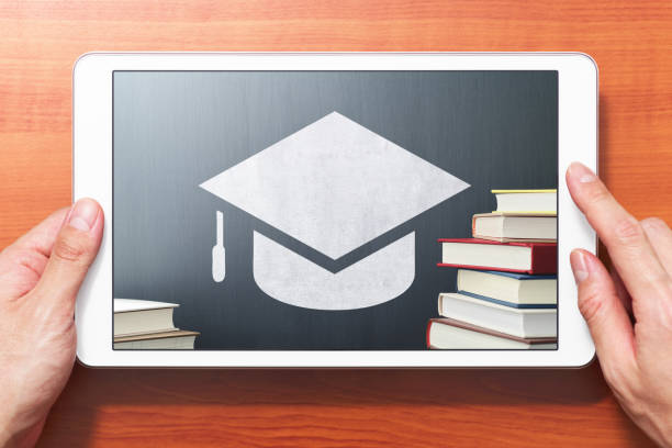 istock E-learning concept image. Closeup of hands touching white tablet computer on wooden desk. 1162448576