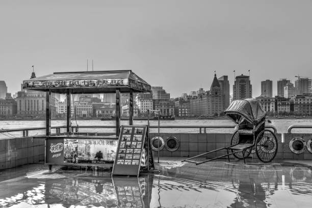 Shanghai, China - November 10, 2014:  Tourist picture stand with rickshaw as prop with The Bund and Huangpu River in the background. Black and while.