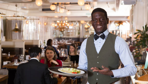 istock Glad waiter who is standing with order in hall 1162457507