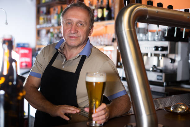 istock Smiling barman is offering unbottled beer to next client 1162457693