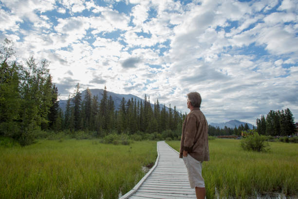 istock Mature man stands on boardwalk over marsh 1162458930