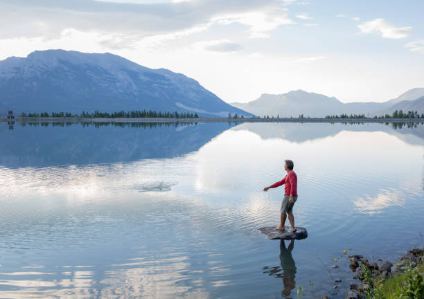 istock Man skips stone along mountain lake in the morning 1162459489