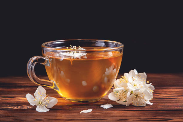 flores de philadelphus en algún lugar llamado jazmín o naranja simulado y taza con té de jazmín fragante en la mesa de madera oscura - jasmine tea jasmine herbal tea drink fotografías e imágenes de stock