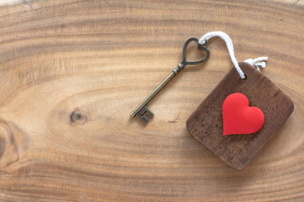House key in heart shape with home keyring on old wood background decorated with mini heart, home sweet home concept, copy space stock photo
