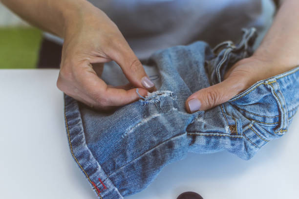 istock women's hands, a tailor sews clothes at a table on which spools of thread lie 1162472784