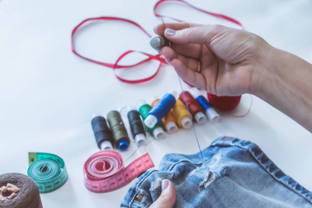 istock women's hands, a tailor sews clothes at a table on which spools of thread lie 1162472987