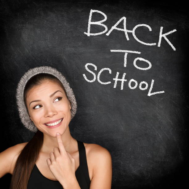 Back to school chalkboard - woman student thinking by blackboard. Female college university student girl thinking Back to School text. Modern trendy cool ethnic Asian Caucasian student in her 20s.