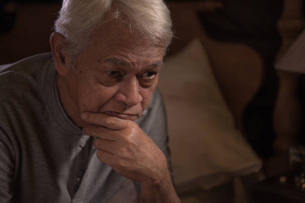 A depressed senior person sitting in bed cannot sleep from insomnia