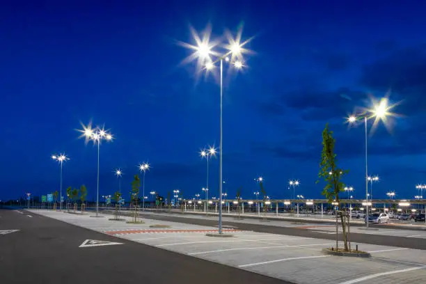 Photo of big modern empty parking lot with bright LED street lights at night