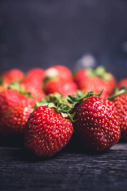 Ripe and juicy strawberries on the dark rustic background