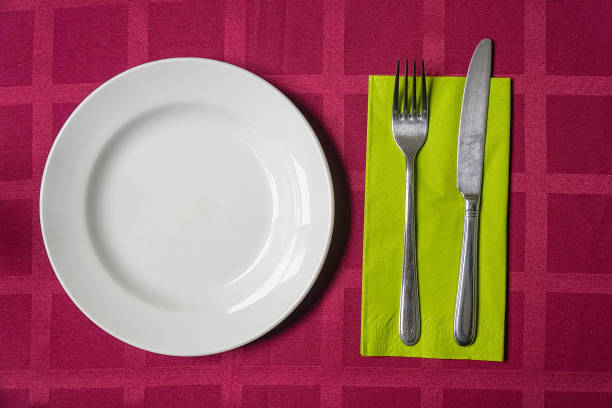 istock White plate, fork and knife on a napkin 1162483263