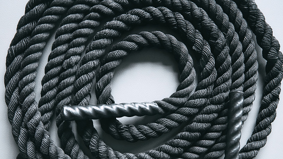 Close up of black battle rope on a gray backgound. Sport and fitness equipment. Functional training. Exercises concept