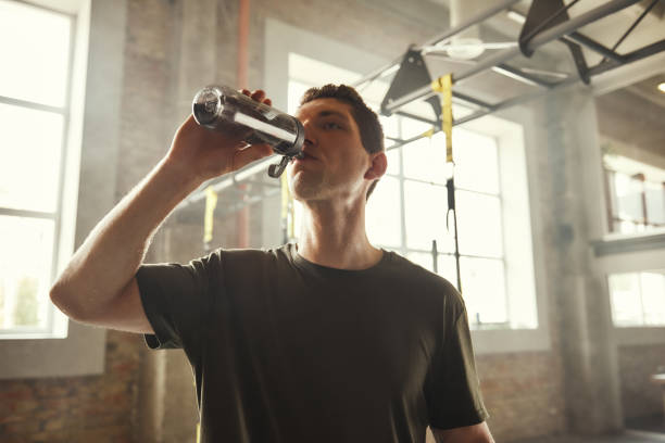 istock Refreshing. Young athletic man drinking fresh water from the bottle while exercising at gym 1162483335