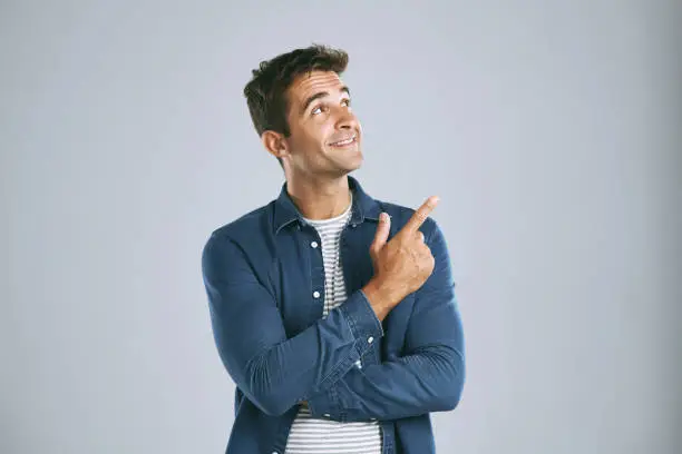 Cropped shot of a man pointing up against a grey background